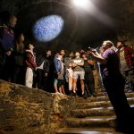 People look at torch on the ceiling of a dungeon