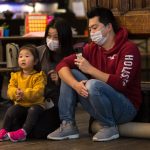 Family wearing masks watch an activity