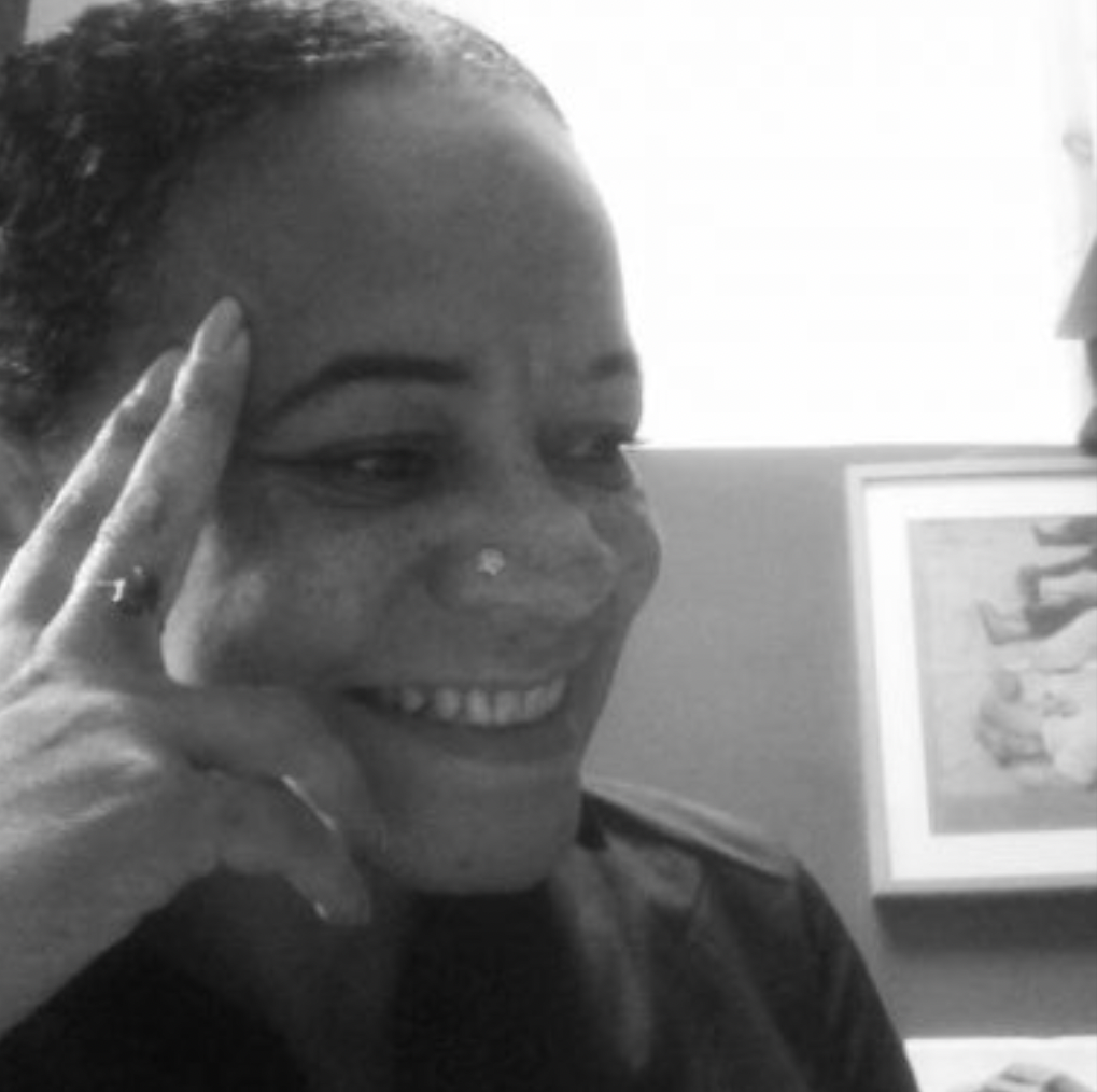 Photo of Dawn Cameron - black and white image of smiling person sat with her hand resting on her head.