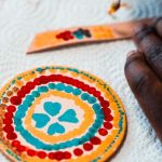 Participant painting bright colours onto a leather circle.