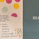 A Beauty Project Lab book open on two pages. One page has yellow and pink circles and writing by a research participant. The other page is green with the word Beauty.