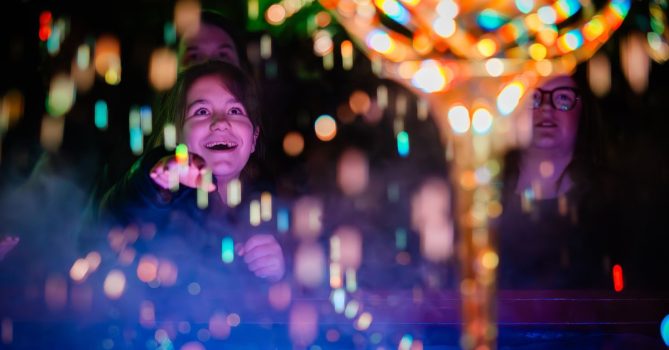 A person with a look of wonder is surrounded by bright twinkling lights.