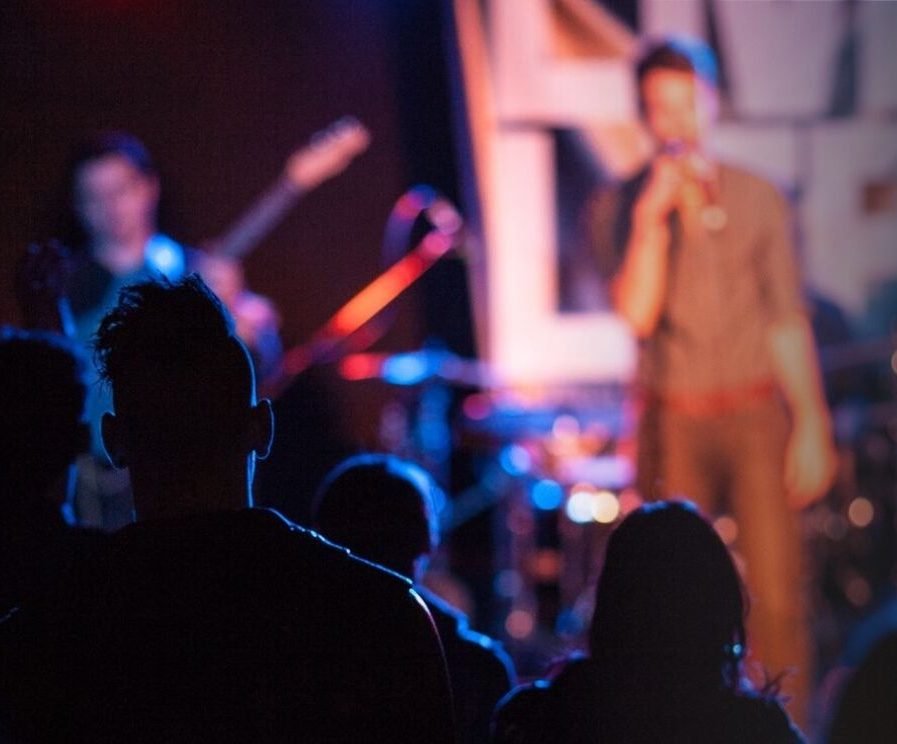 A crowd of young people watching a singer perform on stage.