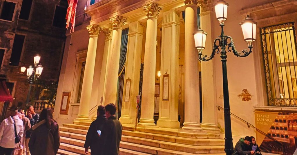 Exterior photo of the front of a traditional opera house at night.